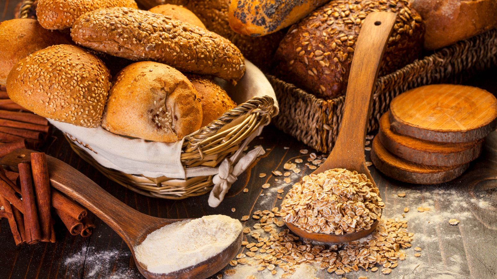 Assorted whole grain bread with flour and oats on a rustic wooden table