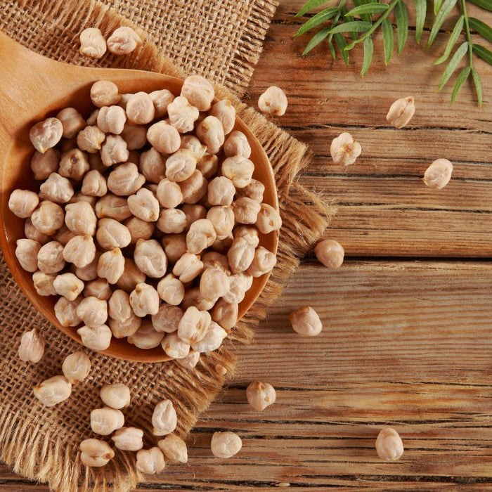 Wooden spoon with dried chickpeas on rustic wooden surface