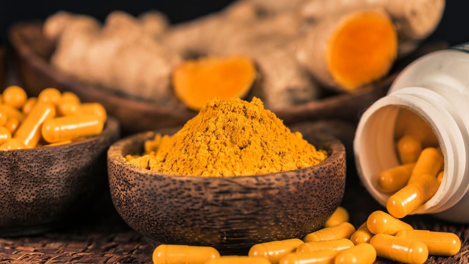 Turmeric capsules and powder in bowls for natural supplement use
