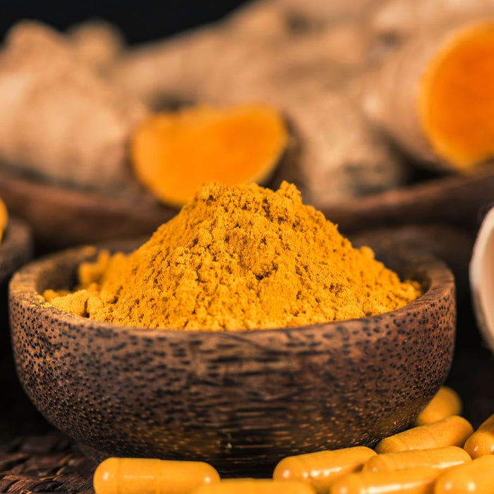 Turmeric capsules and powder in bowls for natural supplement use