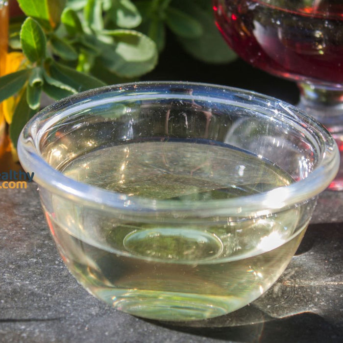Glass bowl of sherry vinegar with herbs and natural extracts outside