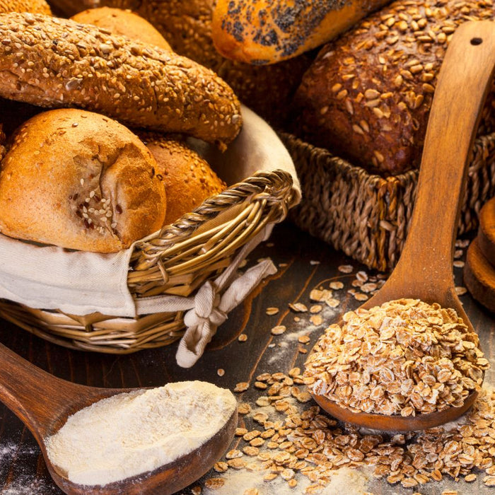 Assorted whole grain bread with flour and oats on a rustic wooden table