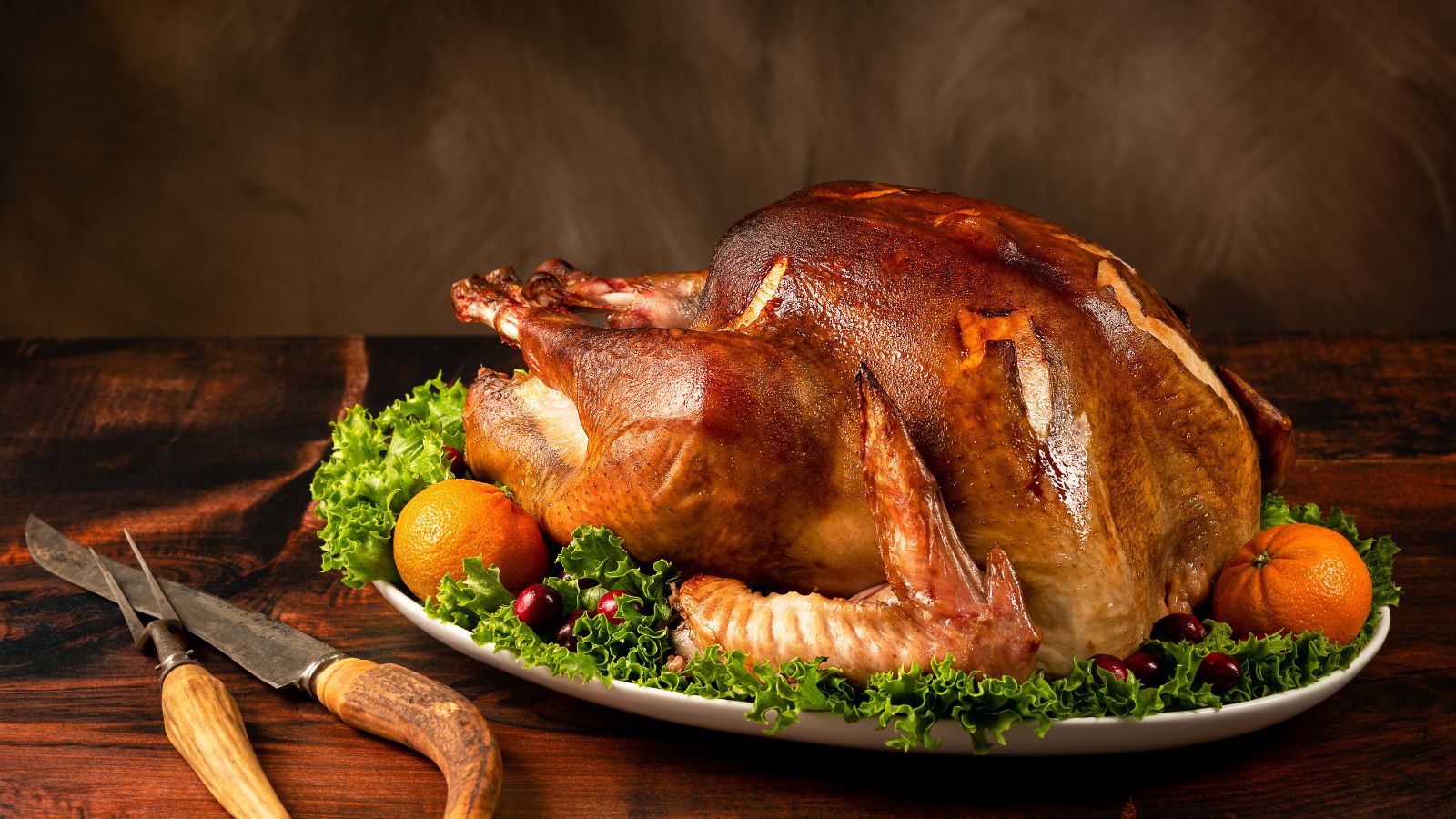 Perfectly roasted turkey on a platter with lettuce, oranges, cranberries