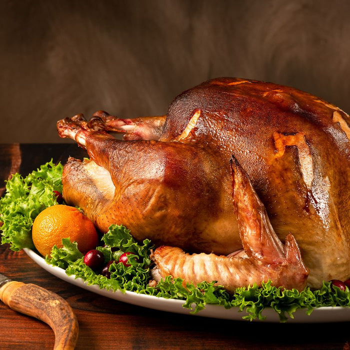 Perfectly roasted turkey on a platter with lettuce, oranges, cranberries