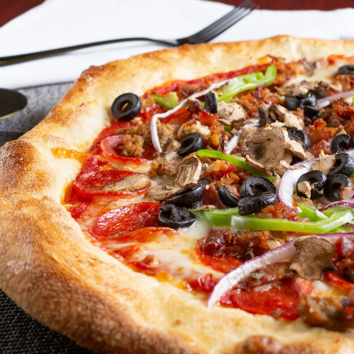 Close-up of loaded pizza with olives, mushrooms, and peppers.