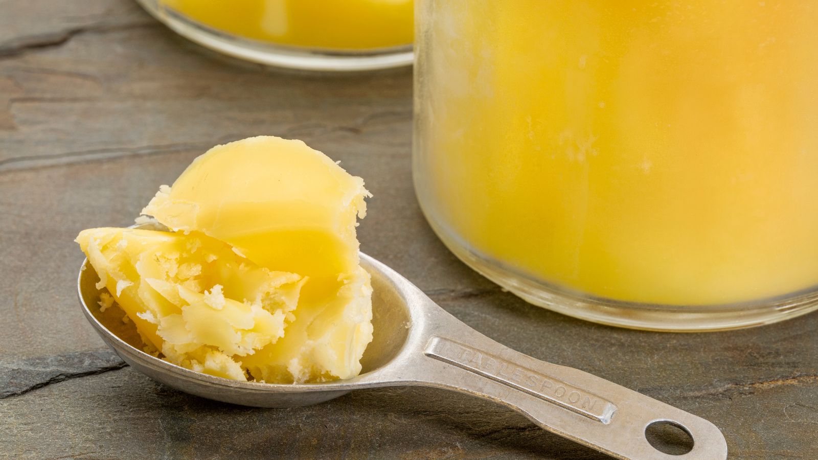 Tablespoon of ghee with jars in the background.