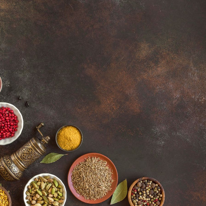 Collection of herbs and spices in bowls on rustic dark background