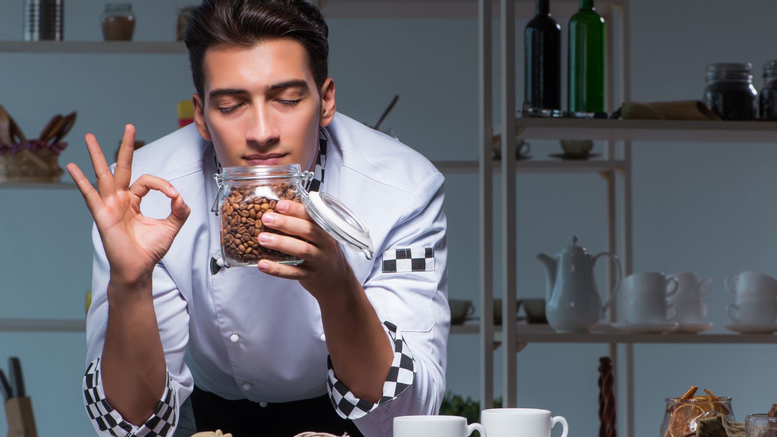 Barista smelling fresh coffee beans from a glass jar