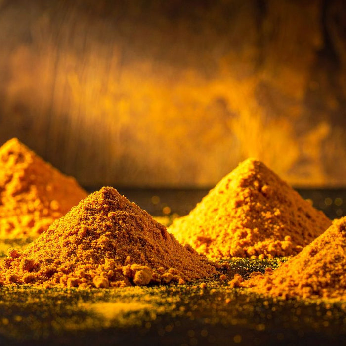 Mounds of golden turmeric powder arranged on dark surface
