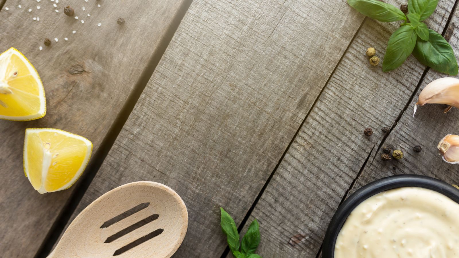 Rustic kitchen table with lemon wedges, garlic, herbs, and cream of tartar sauce
