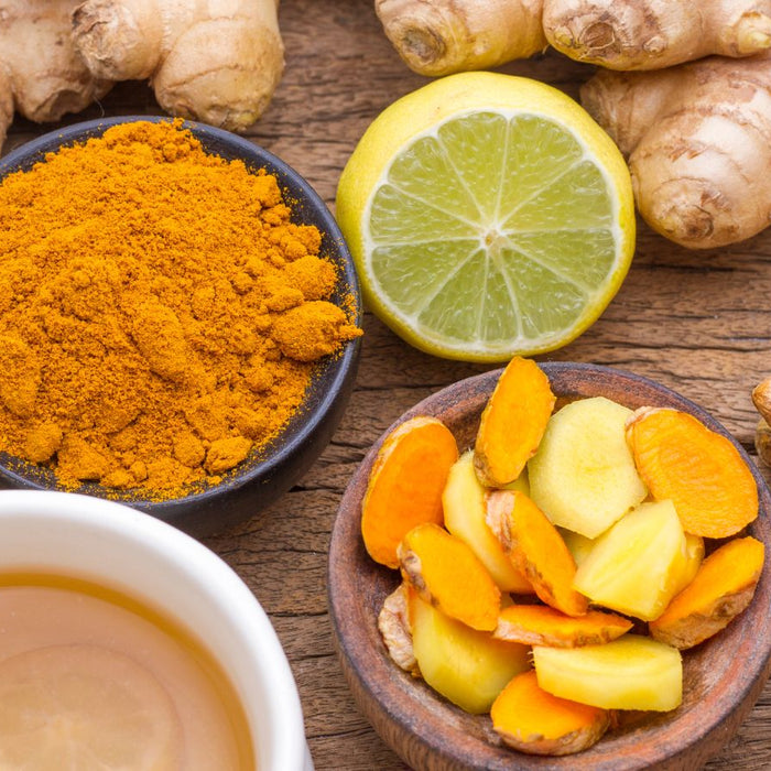 Turmeric, ginger, lemon slices, and tea arranged on rustic wood table