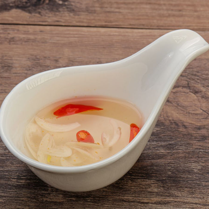 Vinegar fish sauce with garlic and chili in white ceramic dipping bowl.