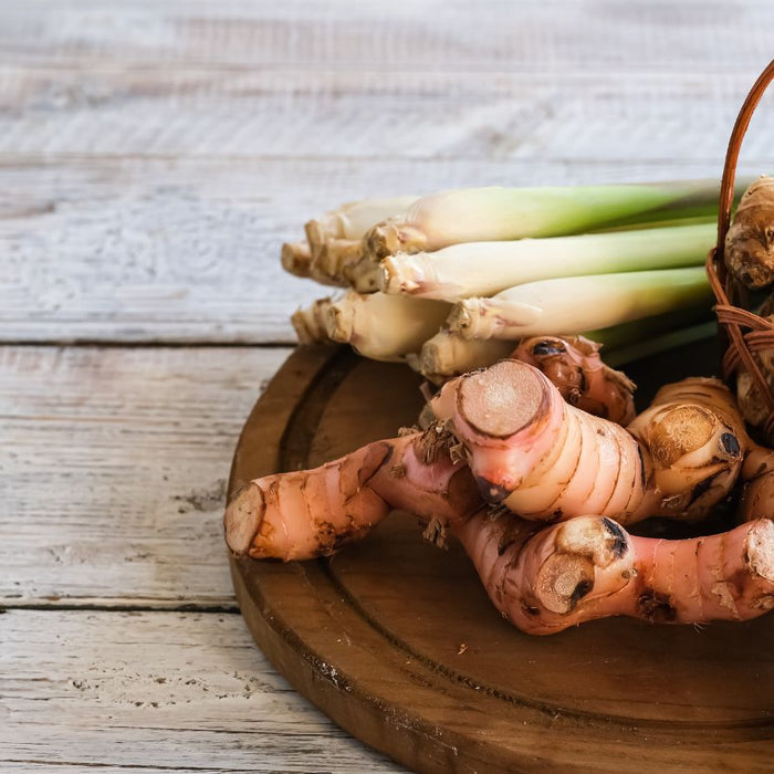 Fresh ginger roots and lemongrass stalks on wooden round board