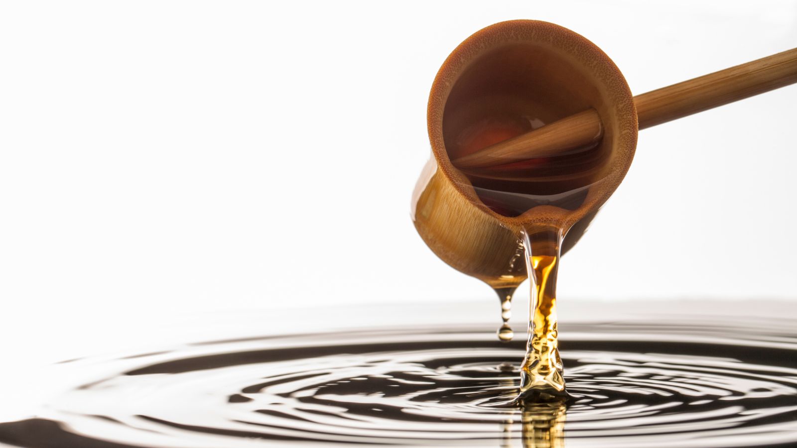 Vinegar being poured from a bamboo ladle into dark liquid.