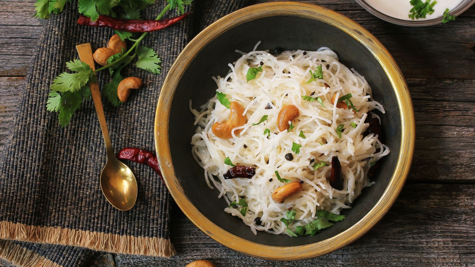 Vermicelli noodles with cashew nuts and spices in a brass bowl.