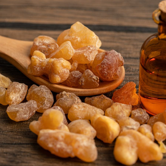 Myrrh resin and essential oil bottle on wood surface