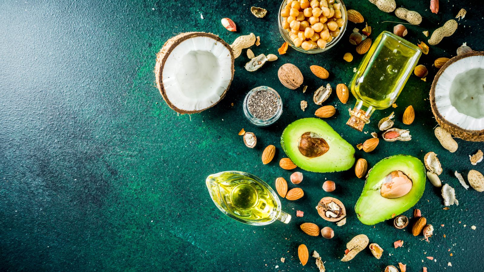 Healthy fats with avocado, coconut, nuts, and chia seeds on table
