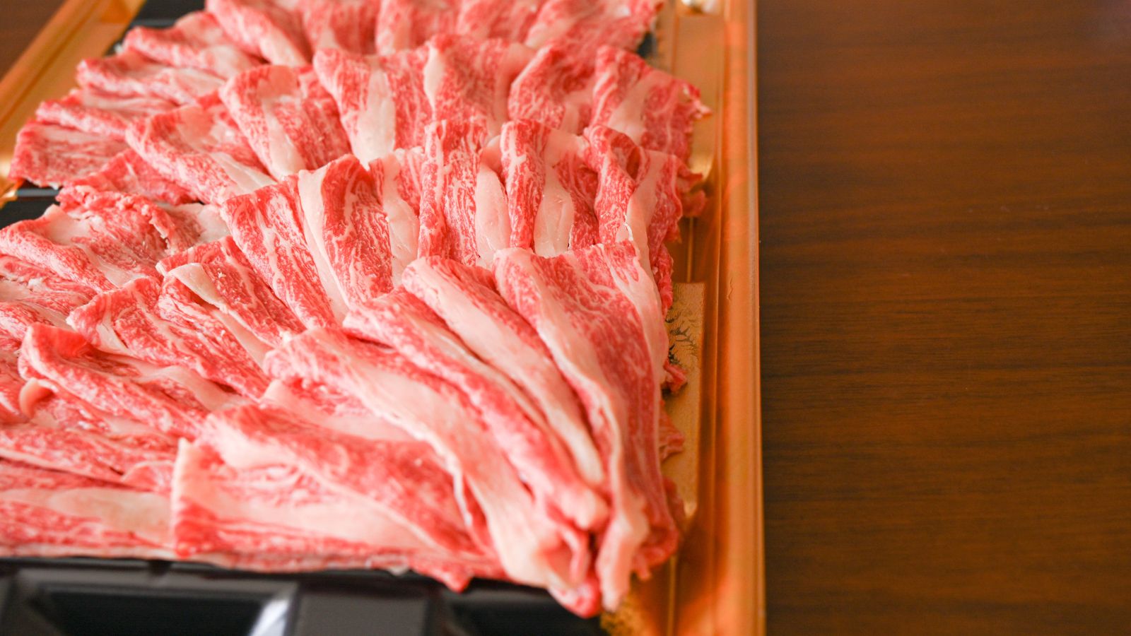 Thinly sliced Wagyu beef arranged in plastic tray.