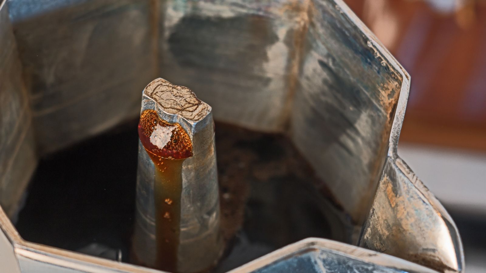 Brewing coffee in a moka pot with fresh espresso dripping