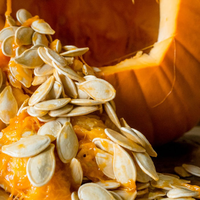 Carved pumpkin spilling bright pulp and seeds onto a wooden board.