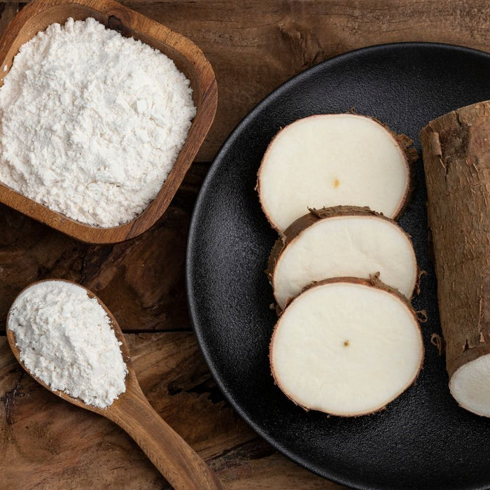 Image 3: Sliced cassava root with tapioca flour in bowl and wooden spoon.