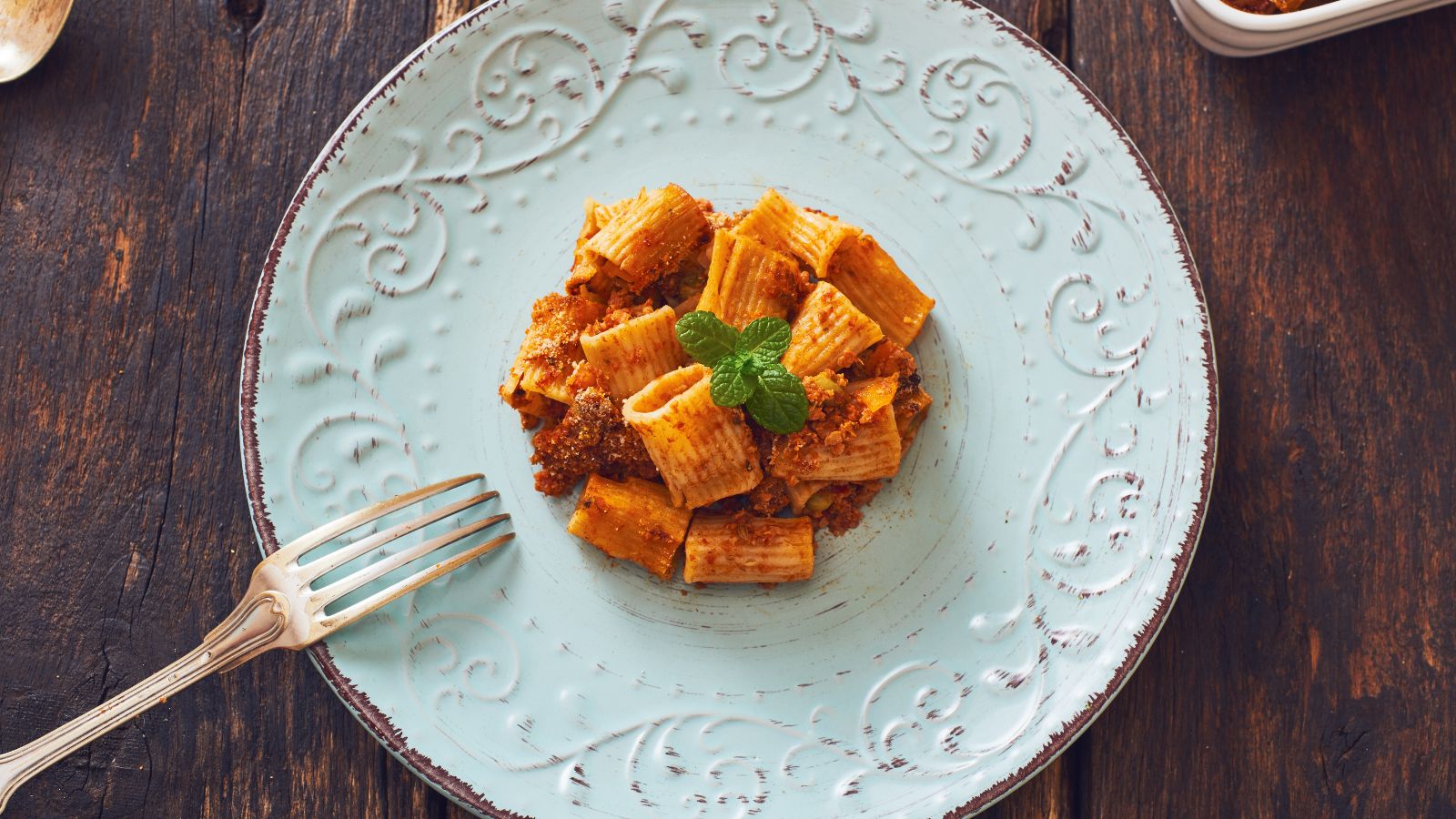 Plate of rigatoni pasta with veggie pasta sauce and mint on vintage plate