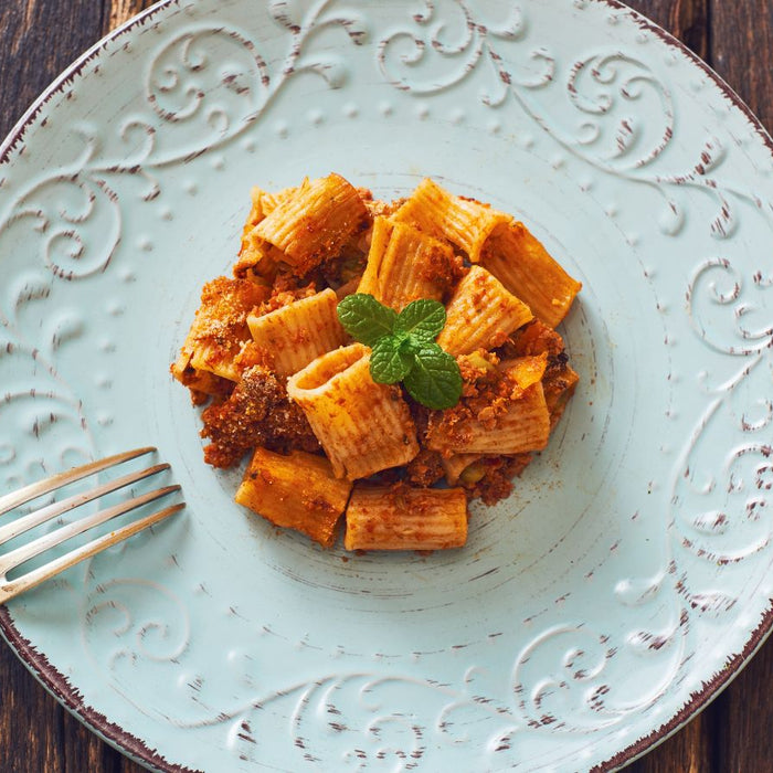 Plate of rigatoni pasta with veggie pasta sauce and mint on vintage plate