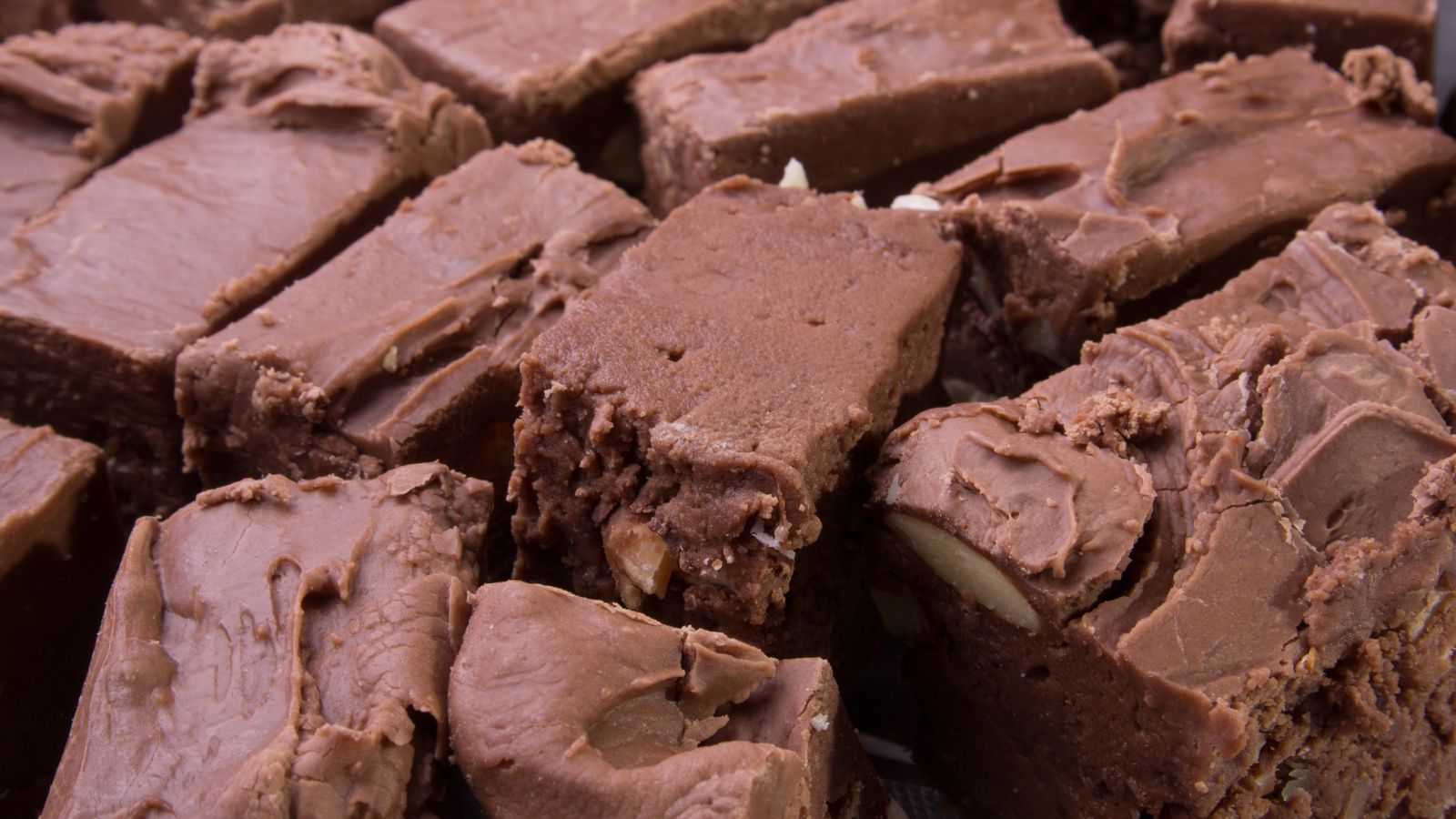 Close-up of rich chocolate fudge squares with visible chunks of nuts