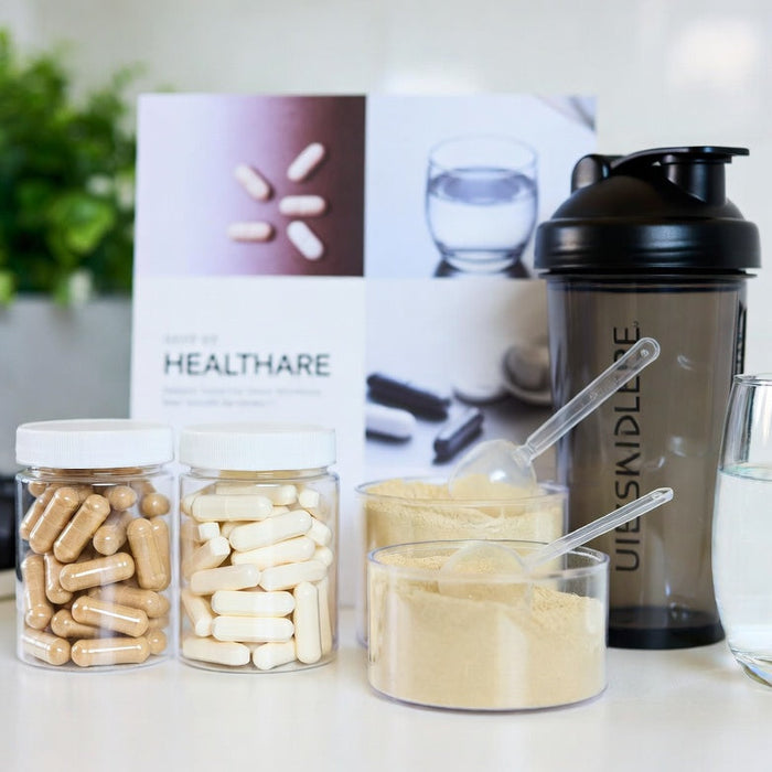 Peptide capsules, collagen powder, shaker bottle, and water on counter