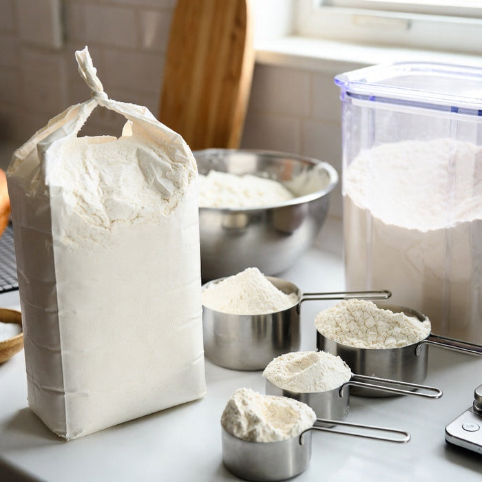 Flour bag, measuring cups, and storage container on baking counter