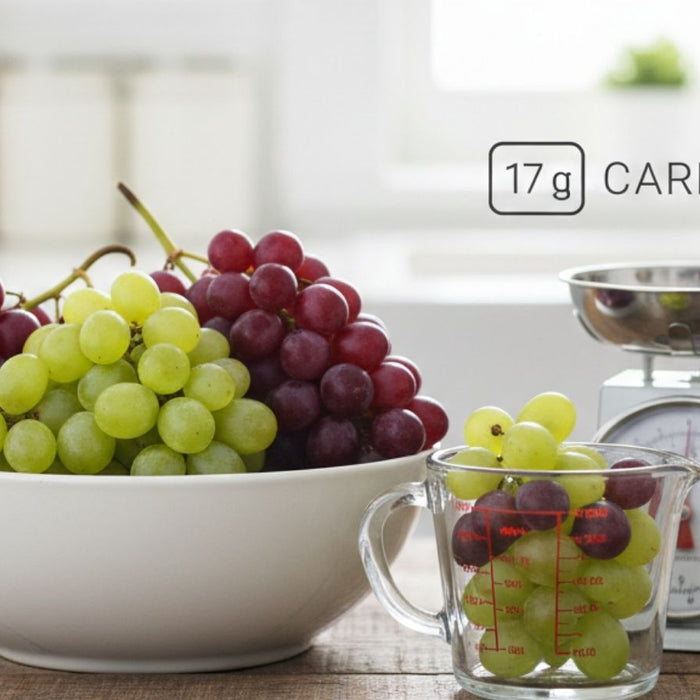Bowl of grapes with measuring cup and scale showing carb content