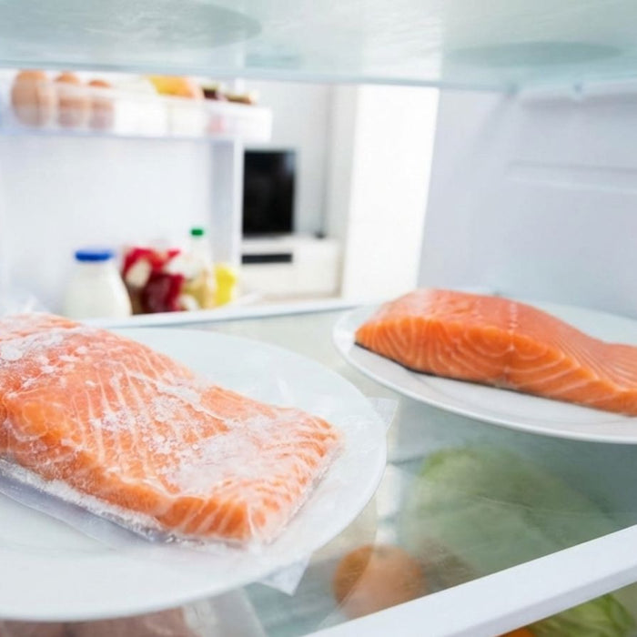 Fresh and frozen salmon fillets on plates inside open refrigerator