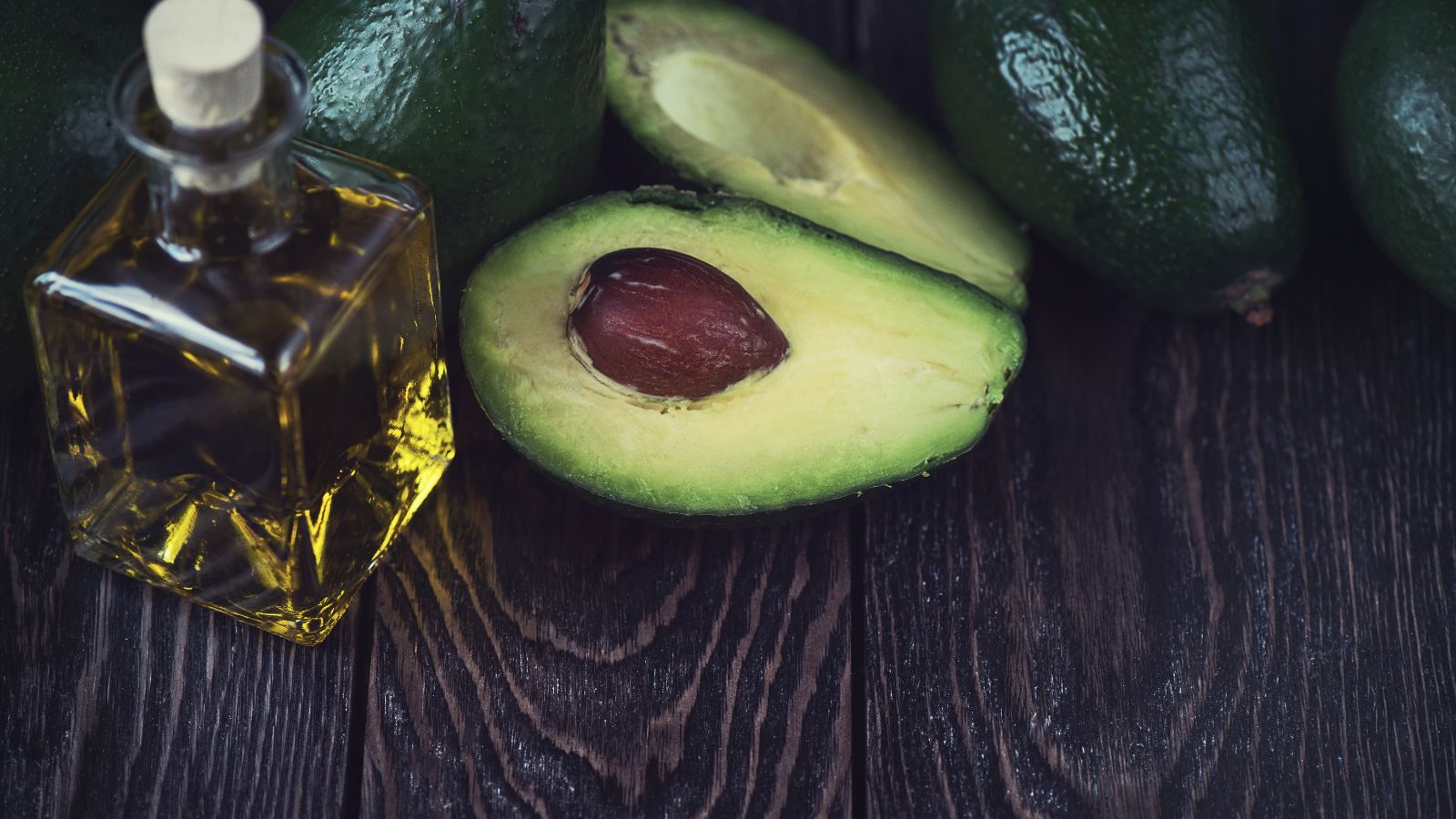 Avocado with seed and a glass bottle of healthy avocado oil