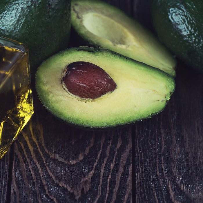 Avocado with seed and a glass bottle of healthy avocado oil