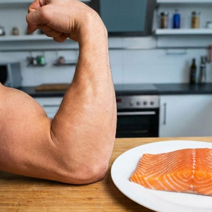 Muscular arm flexing beside raw salmon fillet on kitchen counter