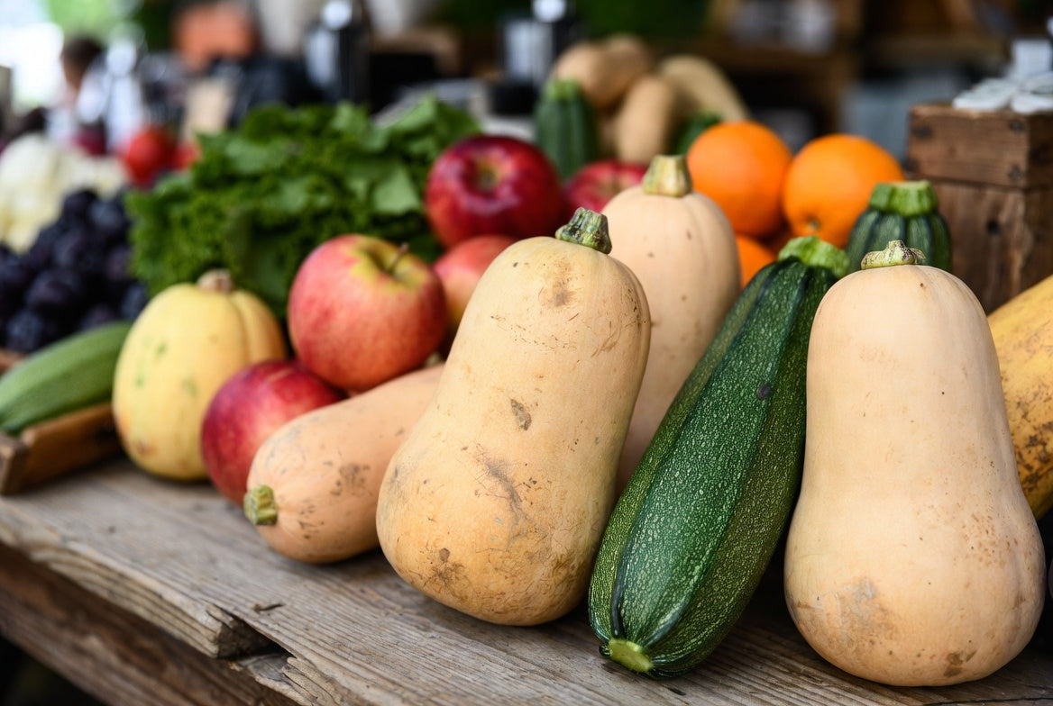 Fresh squash varieties arranged with fruits and vegetables on table