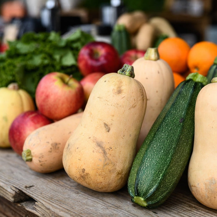 Fresh squash varieties arranged with fruits and vegetables on table