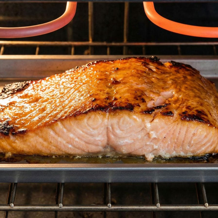 Baked salmon fillet roasting on tray inside oven with heating coils