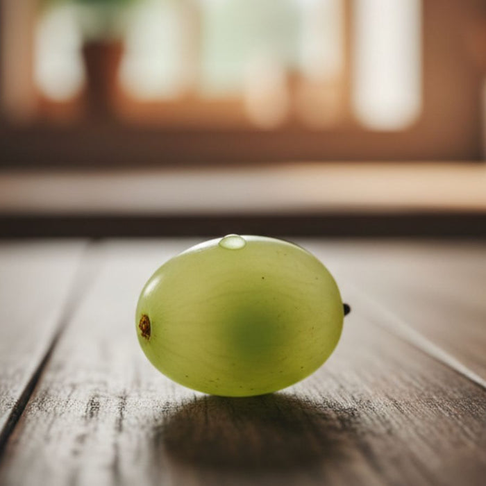 Single green grape resting on wooden surface close-up