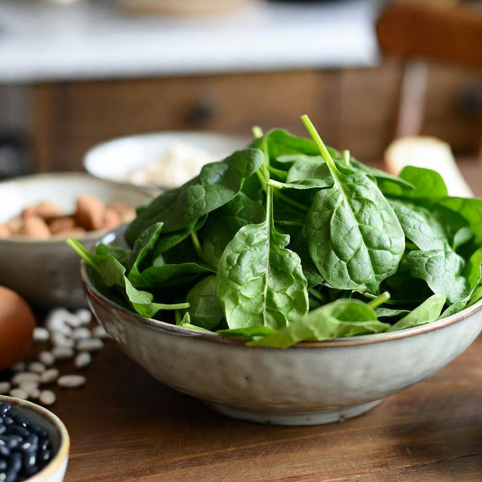 Fresh spinach leaves with eggs, beans and nuts on wooden table