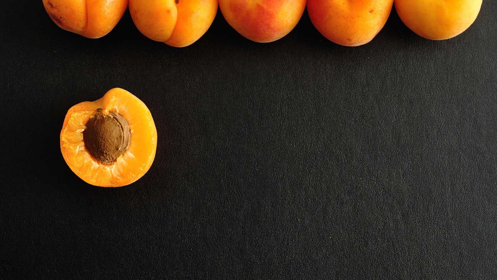 Fresh apricot half and whole fruits on black background