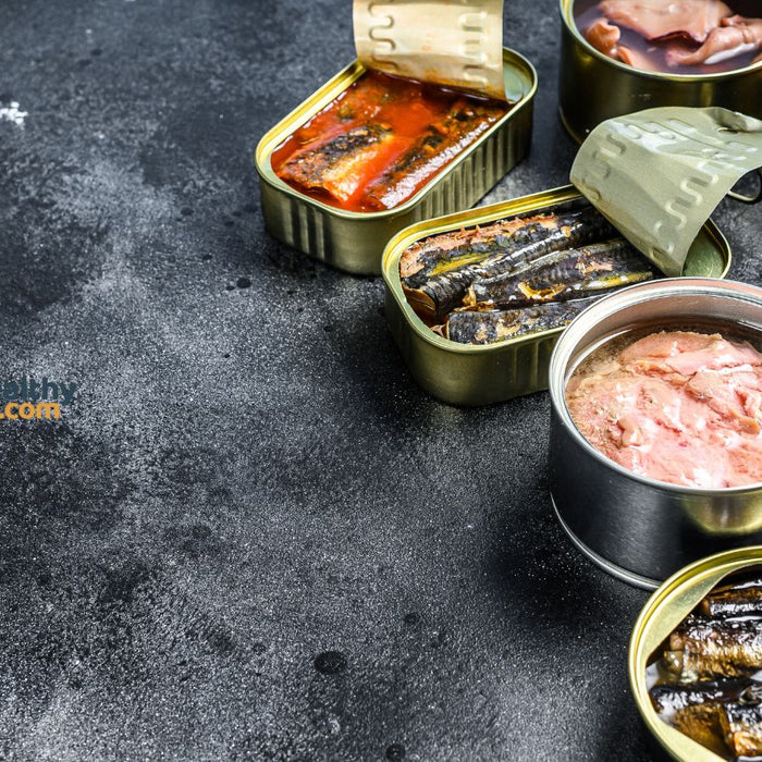 Assorted canned tuna and seafood opened on dark stone background