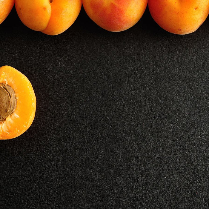 Fresh apricot half and whole fruits on black background