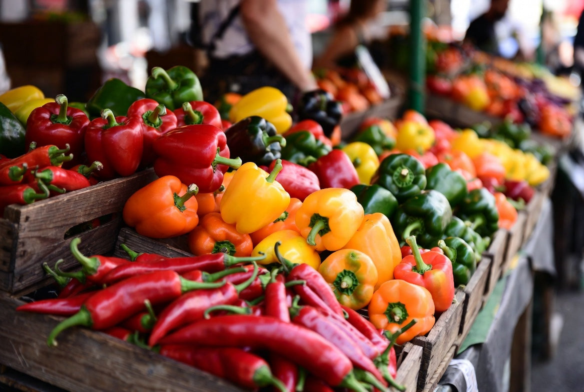 Colorful peppers displayed in wooden crates at outdoor market