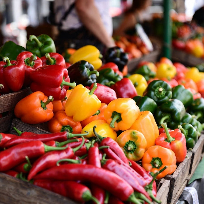 Colorful peppers displayed in wooden crates at outdoor market