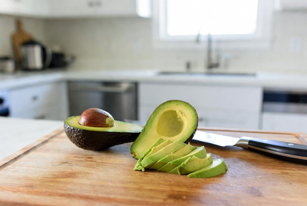 Sliced avocado halves and wedges on a wooden cutting board
