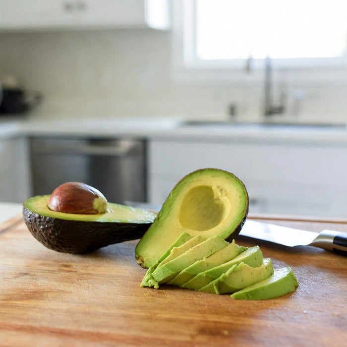 Sliced avocado halves and wedges on a wooden cutting board