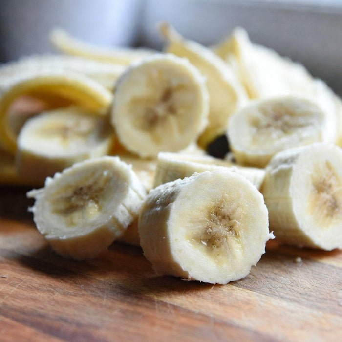 Close-up of sliced bananas on a cutting board with peel in background