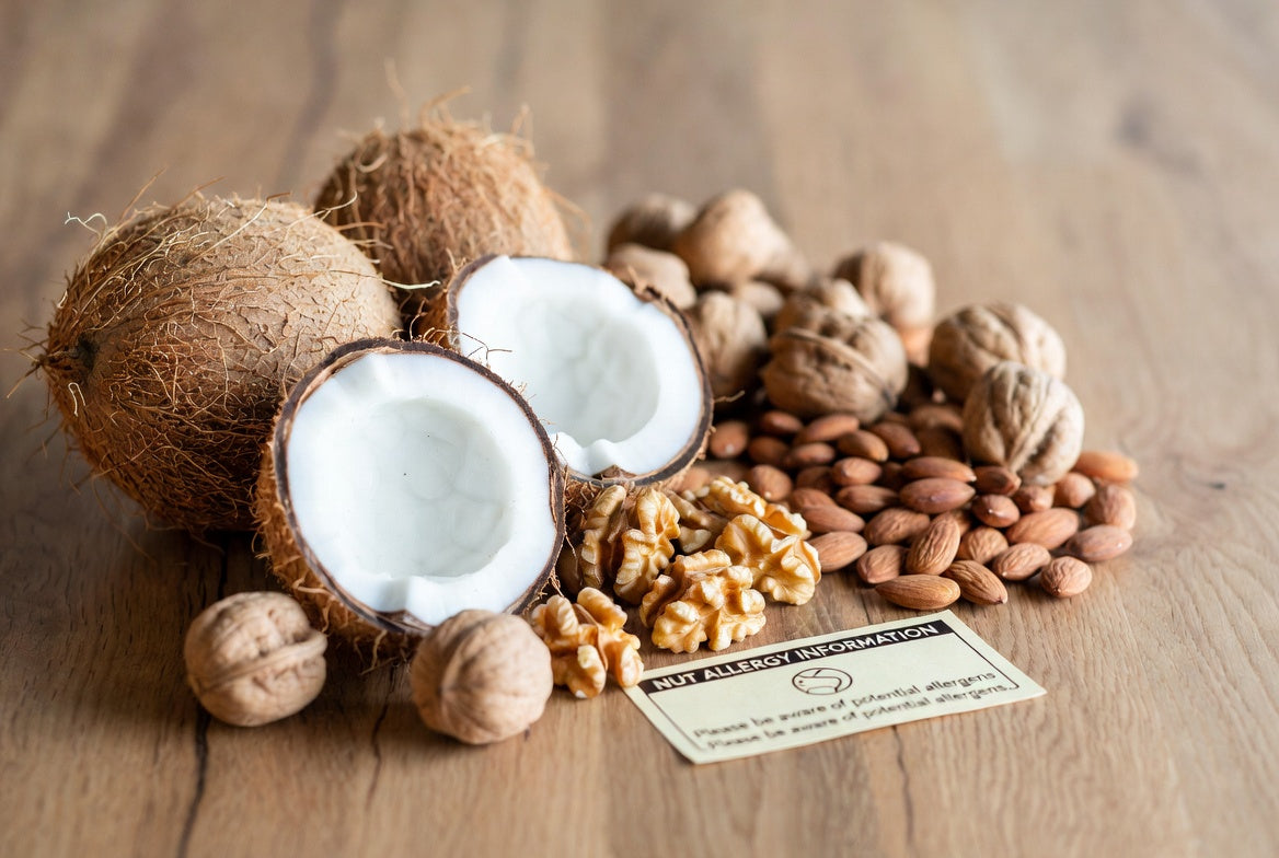 Split coconuts, almonds, and walnuts beside a nut allergy card
