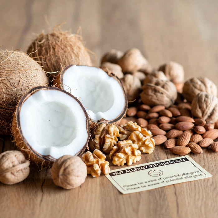 Split coconuts, almonds, and walnuts beside a nut allergy card